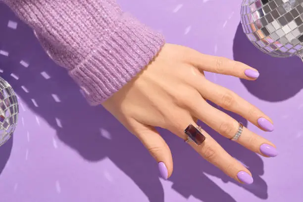 Beautiful womans hands in sweeter with purple fashionable spring nail design. Manicure, pedicure beauty salon concept.